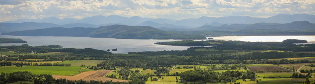 Landscape view looking across farmland, a lake, and mountains. 